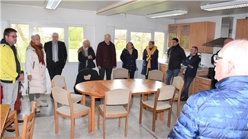 In der Containeranlage in Schwei: Vereinsvorsitzende Sabine Minnemann (hinten links) erläutert den Kommunalpolitikerinnen und Politikern die Raumaufteilung.