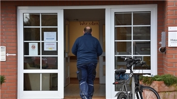 Das Foto zeigt einen Mann, der in ein Pflegeheim geht. 