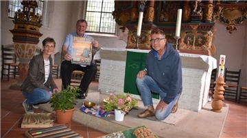 Zwei Männer und eine Frau vor einem Altar