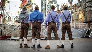 In der traditionellen Tracht beobachten die Männer ein Fahrgeschäft. 
