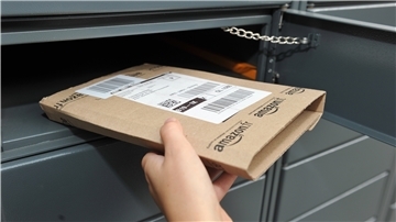 Eine Hand schmeißt ein Paket in einen Briefkasten.