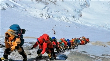 In einer langer Schlange klettern Bergsteiger auf einem Pfad knapp unterhalb von Lager vier.