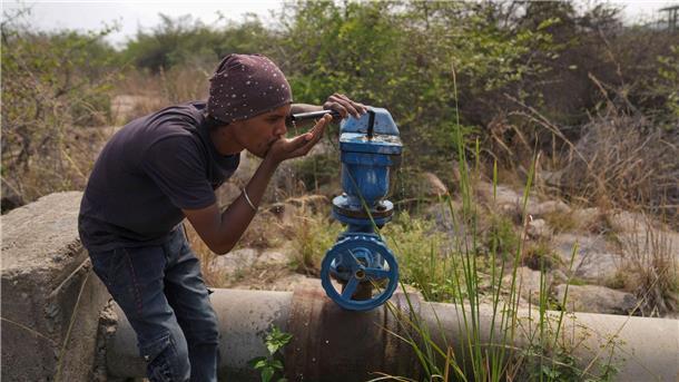 UN-Wassergipfel endet mit globalem Aktionsplan In Indien trinkt ein Mann Wasser aus einer undichten Wasserstelle.