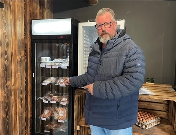 Vogelgrippe: Elmloher Geflügelhalter nervös, aber auch gelassen Ein Mann mit Brille zeigt auf einen Kühlschrank, in dem Wurst lagert.
