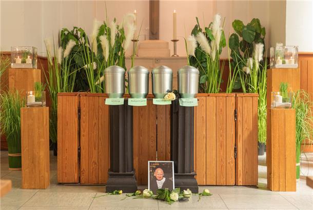 Vier Urnen vor einem Altar. Davor das Foto eines Verstorbenen.