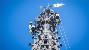 Angeseilte und behelmte Arbeiter aus Thüringen sanieren an Seilen gesichert die Turmspitze der Großen Kirche Bremerhaven.