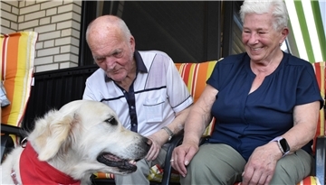 Ein alter Mann und eine alte Frau, davor sitzt ein Hund.