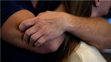 Nahaufnahme aus einer Angriffssituation: Ein Mann hat die Arme um den Hals einer Frau gelegt.
