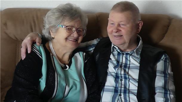 Ein Mann und eine Frau sitzen auf einem Sofa und strahlen.