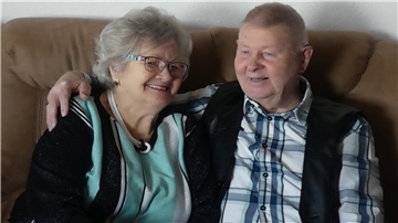 Ein Mann und eine Frau sitzen auf einem Sofa und strahlen.