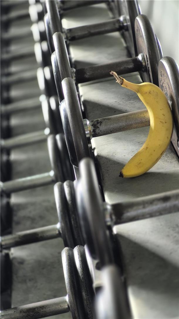Bananen-Power: Dein schneller Energiekick vor dem Sport Eine Banane mit Kurzhanteln.