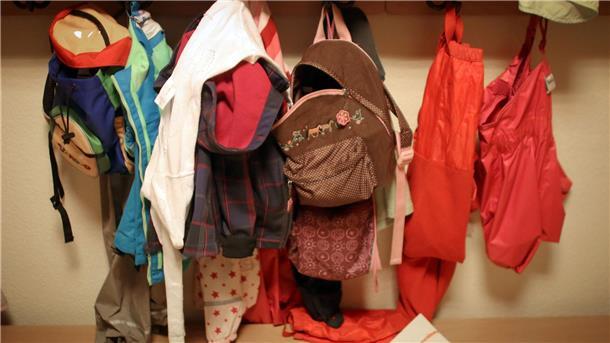 Jacken und Rucksäcke von Kindern in der Garderobe einer Betriebskita.