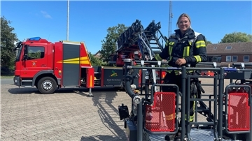 Frau in Korb der Rettungsleiter eines Feuerwehrautos