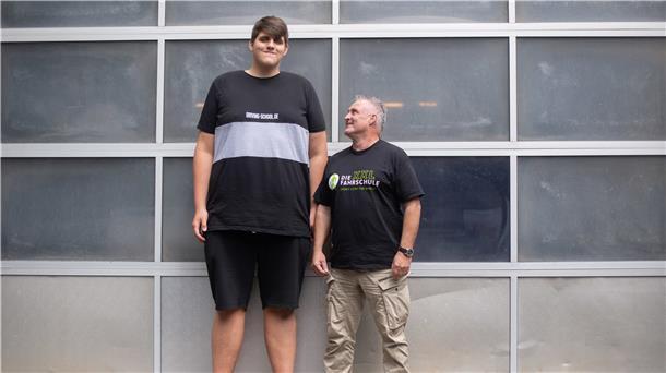 Jannik Könecke (l) und Jörg Vespermann, Fahrlehrer und Geschäftsführer Berufskraftfahrer-Akademie-Nord GmbH, stehen vor einem Garagentor.