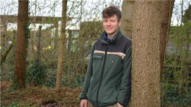 Jasper Robin Krüger lehnt an einem Baum und blickt in die Kamera.