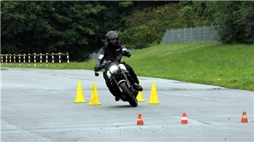 Ein Motorradfahrer legt sich auf regennasser Fahrbahn in die Kurve.