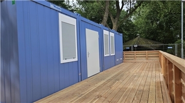 Bürocontainer, davor eine Holzterrasse mit Geländer