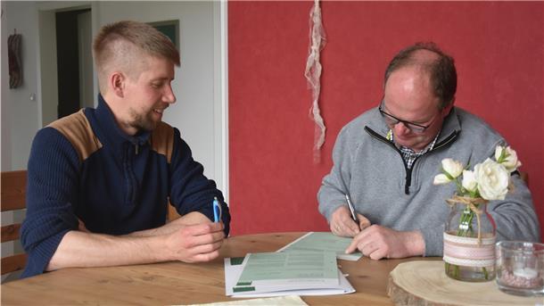 Maisanbau: Für Biobauern eine große Herausforderung Das Foto zeigt den frischgebackenen Biobauern Jan Kaiser bei der Vertragsunterzeichnung. Daniel Bischoff, Erzeuger- und Umstellungsberater bei Bioland, schaut ihm dabei zu.
