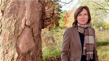 Frau steht neben einem Baum