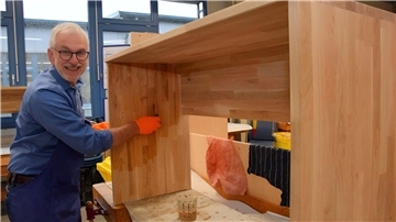 Ein Mann bearbeitet einen Holztisch