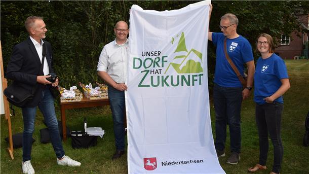 Jury-Leiter Ralf Gebken (von links) vom Landwirtschaftsministerium überreichte bei der Bereisung in Rhade eine Fahne zum Landeswettbewerb „Unser Dorf hat Zukunft“ an Bürgermeister Marco Mohrmann sowie die Ratsmitglieder Olaf Wendelken und Raphaela Vink, die durch die Präsentation führten.  