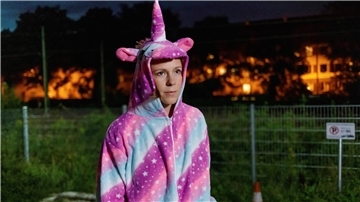 Frau in Einhorn-Kostüm geht draußen spazieren.