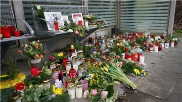 Kerzen und Blumen stehen und liegen im Bahnhof Brokstedt in einem Wartehäuschen.