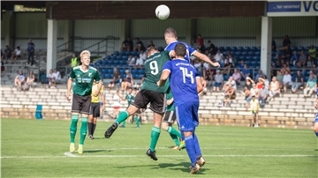 Sechs Männer stehen in Trikots auf dem Fußballplatz.