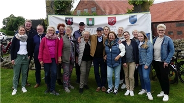 16 ehrenamtliche Helferinnen und Helfer aus Laven stehen Seite an Seite. Hinter ihnen hängt ein großes Transparent zur Gemeinde Schiffdorf.