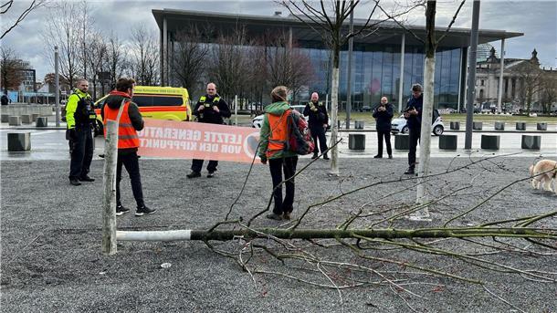 Klimaschutz-Demonstranten stehen an einem gefällten Baum am Bundeskanzleramt.