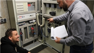 Klimaschutzmanager Julian Fricke (rechts) und Elektromeister Marcel Holtmann kontrollieren Stromlogger, die den Stromverbrauch detailliert erfassen.