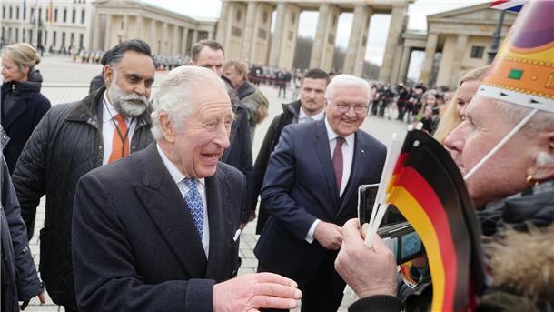Jubelrufe und Fähnchen: Charles und Camilla in Berlin König Charles III. von Großbritannien (vorne l) schüttelt Hände am Brandenburger Tor, Bundespräsident Frank-Walter Steinmeier steht hinter ihm.