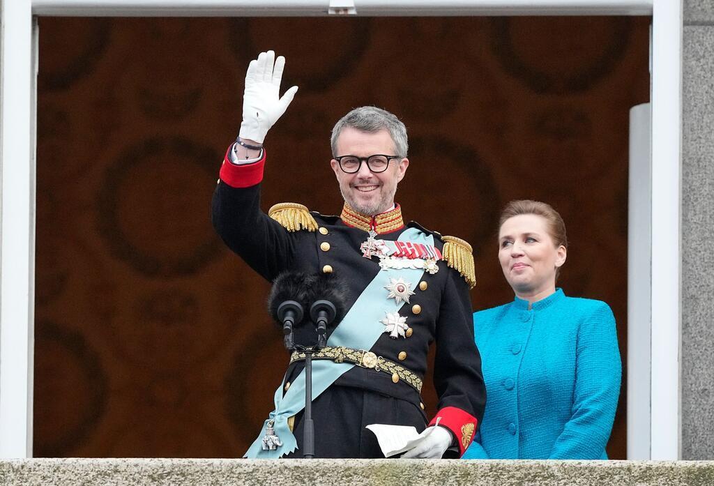 König Frederik X. von Dänemark winkt vom Balkon des Schlosses Christiansborg, während die dänische Ministerpräsidentin Mette Frederiksen zusieht.