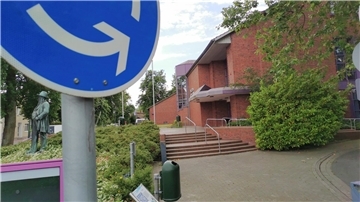 Im Vordergrund ist ein Verkehrsschild zu sehen, dahinter ein größeres Gebäude.