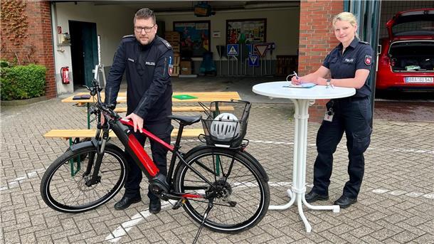 Kostenlose Prävention: Fahrradcodierung schreckt Diebe ab Eine Polizeibeamtin füllt an einem Stehtisch ein Formular aus, neben ihr untersucht ein Polizeibeamte ein Fahrrad.