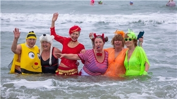 Kostümierte Eisbader vergnügen sich beim Faschingsbaden am Strand von Warnemünde in der 3,8 Grad kalten Ostsee.