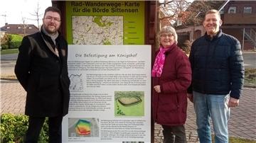 Kreisarchäologe Dr. Stefan Hesse übergibt Stefan Miesner und Erika Jaschinski eine Tafel zur Befestigung beim Königshof.