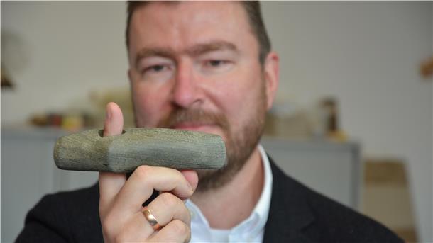 Kreisarchäologe Dr. Stefan Hesse zeigt eine Steinaxt, die in einem 4500 Jahre alten Grab auf dem Hexenberg in Zeven gefunden wurde.