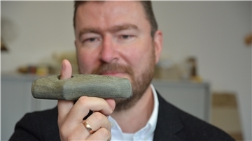 Kreisarchäologe Dr. Stefan Hesse zeigt eine Steinaxt, die in einem 4500 Jahre alten Grab auf dem Hexenberg in Zeven gefunden wurde.