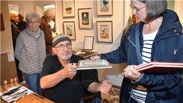 Künstler Ole West signierte seine Werke im Flur des Wohnhauses von Eva Janschek und Jens Schröter. Das Wetter spielte bei der 13. Sommerausstellung in der „Kleinen Galerie am Moor“ nur bedingt mit. 