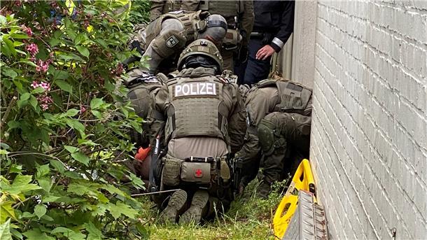 Kurz nachdem der 37-Jährige durch das geschlossene Fenster aus dem ersten Stock des Hauses gesprungen ist, wird der Verletzte von SEK-Beamten am Boden fixiert.