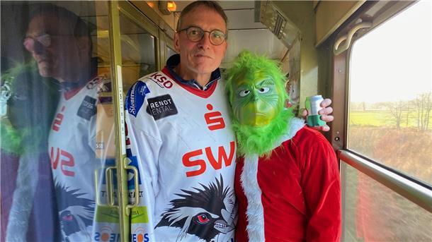 Kurz vor Weihnachten war ein besonderer Gast an Bord: der Grinch (hier mit Pinguins-Fan Jörg). Er zog durch die Abteile und Gänge und triezte die Pinguins-Fans