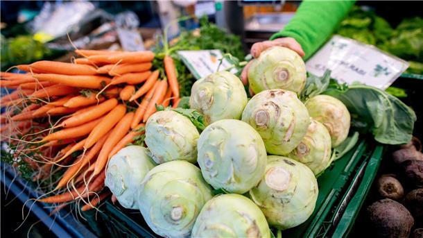  Kohlrabi und Karotten stehen an einem Obst- und Gemüsestand auf einem Wochenmarkt zum Verkauf. 