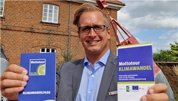 Landrat Stephan Siefken wirbt für die „Mottotour Klimawandel“. Im Hintergrund ist der Braker Telegraph zu sehen, vor dem eine der neun Stationen zu finden ist.