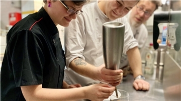 Lea (1. Lehrjahr) und Maximilian Meyer (2. Lehrjahr) richten den Nachtisch an: „Schwarzwälder Kirschtorte aus der Laborküche“. Chef Claus Peter schaut prüfend über die Schulter.