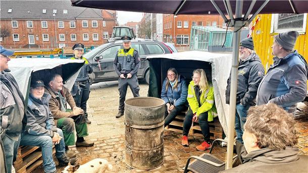 Drei Wochen Protestcamp in Stade: Das sind die Tops und Flops Campteilnehmer und zwei Polizisten stehen oder sitzen rund um die Feuertonne