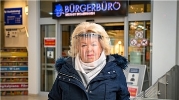 Eine Frau steht mit einem Corona Schutzschild vor dem Bürgerbüro Bremerhaven.