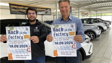 Zwei Männer mit Plakaten vor einer Reihe Autos