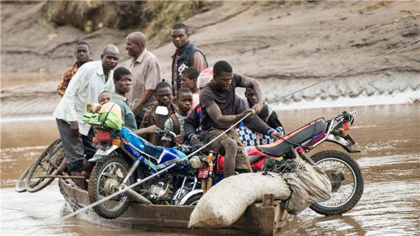 Opferzahl nach Tropensturm „Freddy“ steigt auf 531 Männer transportieren in Malawi ihre geretteten Habseligkeiten mit einem Holzboot.