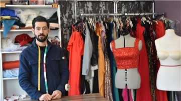 Mahmoud Houseins steht hinter einem Tisch in seiner Nähwerkstatt.